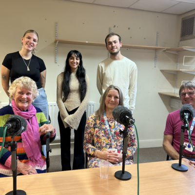 BCU students Maya Davis and Kyle Salmon with lecturer Meera Darji, and podcast guests Joan Fairley, Rachel Barker and Andy Barker at the microphone during podcast recording at St Giles Hospice