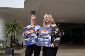 Charlotte Mills, Community Fundraiser, and Lorraine Ward, Regional Manager, holding We're Dying to Tell You Something podcast posters at St Giles Hospice