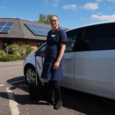 St Giles Hospice nurse Leia Roden standing with equipment case beside a car, ready for a Rapid Response visit